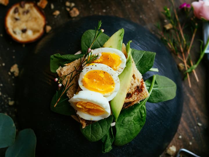 Sliced boiled egg and avocado on toasted bread with spinach