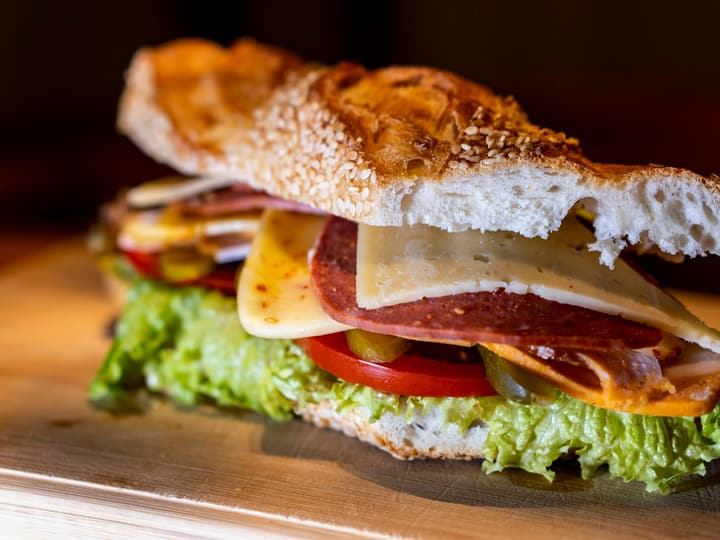 A filled submarine sandwich cut open on a wooden board