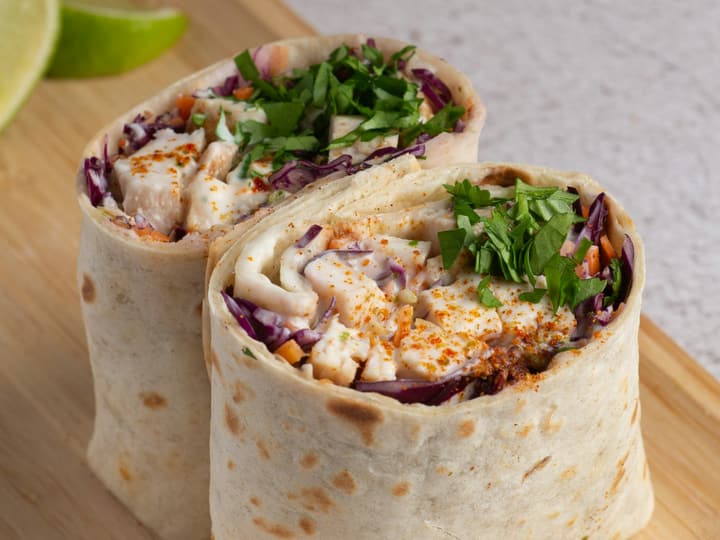 Two filled tortilla wraps cut in half on a wooden board