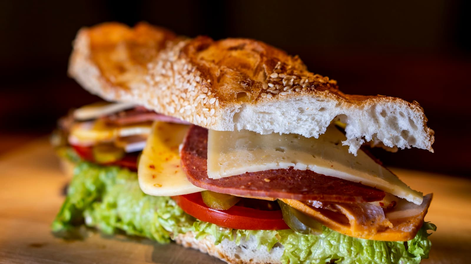 A submarine sandwich on a sesame roll, filled with cold cuts, cheese, lettuce and tomato